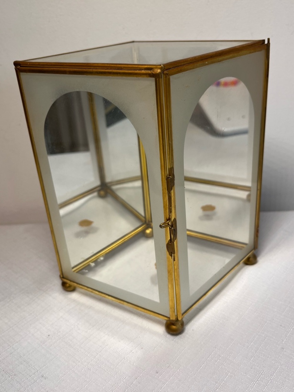 glass display box with gold metal trim. Clear mirrored interior panels